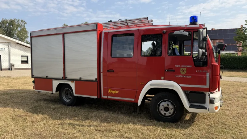 Löschgruppenfahrzeug LF 8 der Feuerwehr Fladderlohausen von der Seite, Rollläden geschlossen, Schiebleiter auf dem Dach.