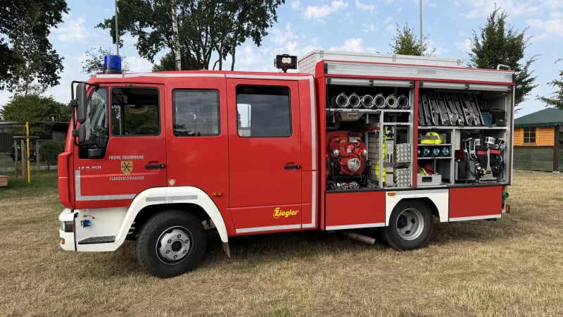 Fahrerseite des LF 8 mit geöffneten Geräteräumen: Tragkraftspritze, Schläuche, Kupplungen und Atemschutzgeräte.