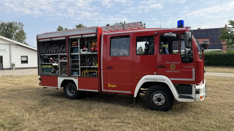 Beifahrerseite des LF 8 mit geöffneten Geräteräumen: Strahlrohre, Werkzeugkisten und Kleingerät in den Regalen.