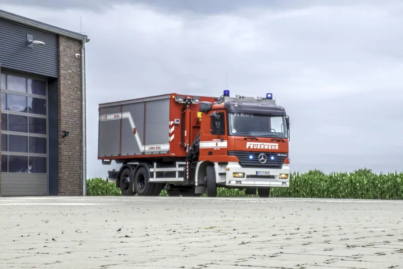 WLF mit Abrollbehälter Rüst von schräg vorn vor dem Feuerwehrhaus.