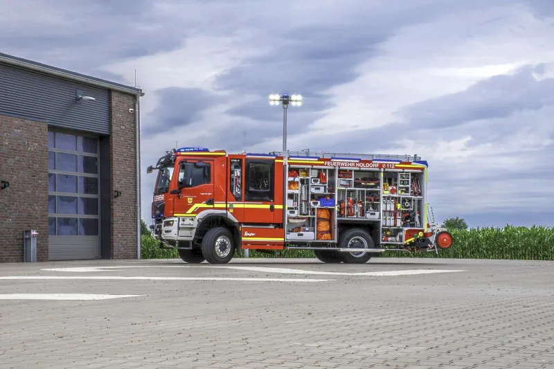 HLF 1 von der Seite mit geöffneten Geräteräumen und ausgefahrenem Lichtmast.
