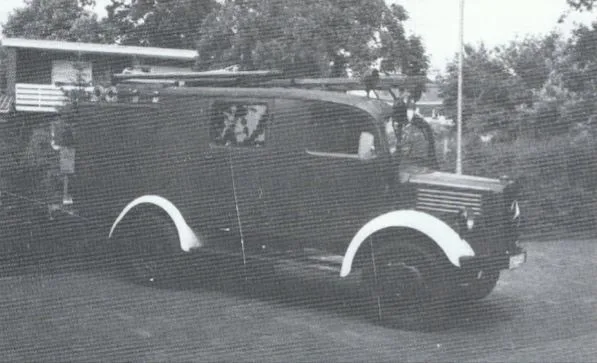 Schwarz-Weiß-Foto des LF 8-TSA, ein Mercedes-Benz L 1500 mit hellen Kotflügelkanten, vor einem Gebäude.