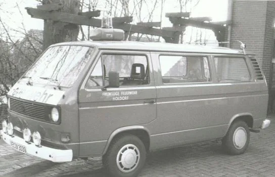 Schwarz-Weiß-Foto eines VW-Transporters mit Dachaufbau und Aufschrift Freiwillige Feuerwehr Holdorf.