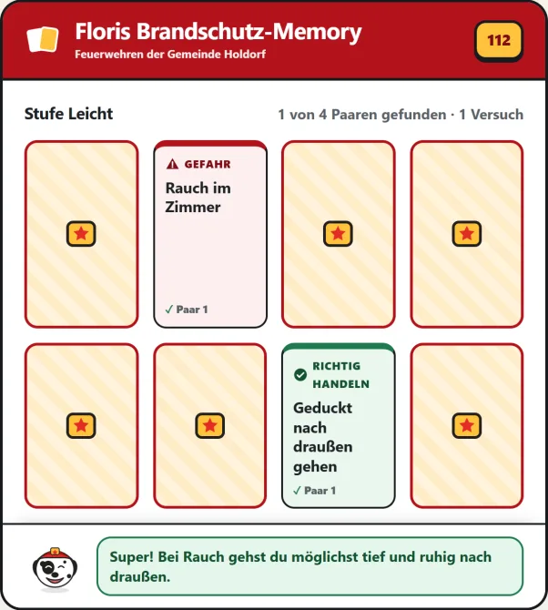 Spielfeld des Brandschutz-Memorys in der Stufe Leicht: verdeckte Karten und ein aufgedecktes Paar aus der Gefahr „Rauch im Zimmer“ und dem Verhalten „Geduckt nach draußen gehen“, darunter Floris Lob.