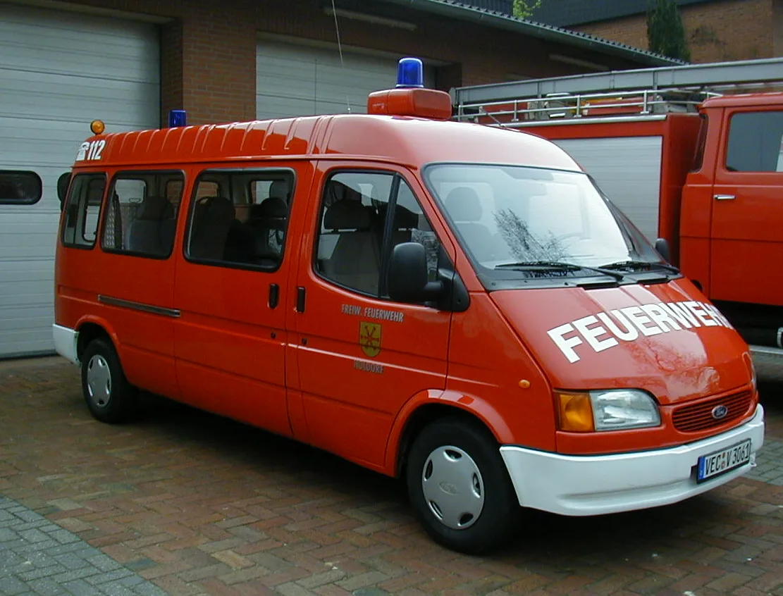 Roter Ford Transit der Feuerwehr Holdorf mit Blaulicht, vor den Toren des Feuerwehrhauses.