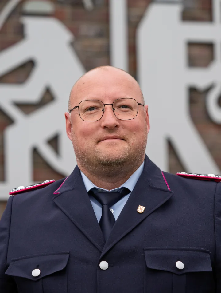 Porträt von Daniel Fraß mit Brille in dunkelblauer Uniform.